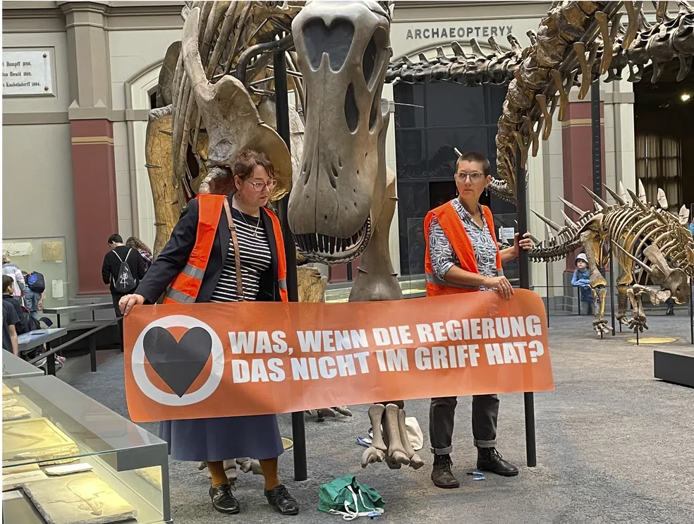 Ativistas pelo clima colam as mãos em exposição de dinossauros